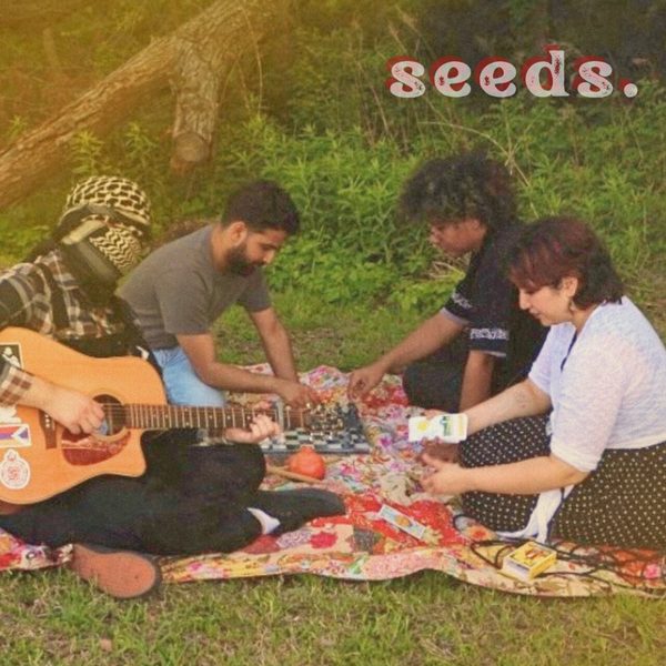 Cover of the Seeds EP by The Pomegranates, the band sitting on a quilt in the grass